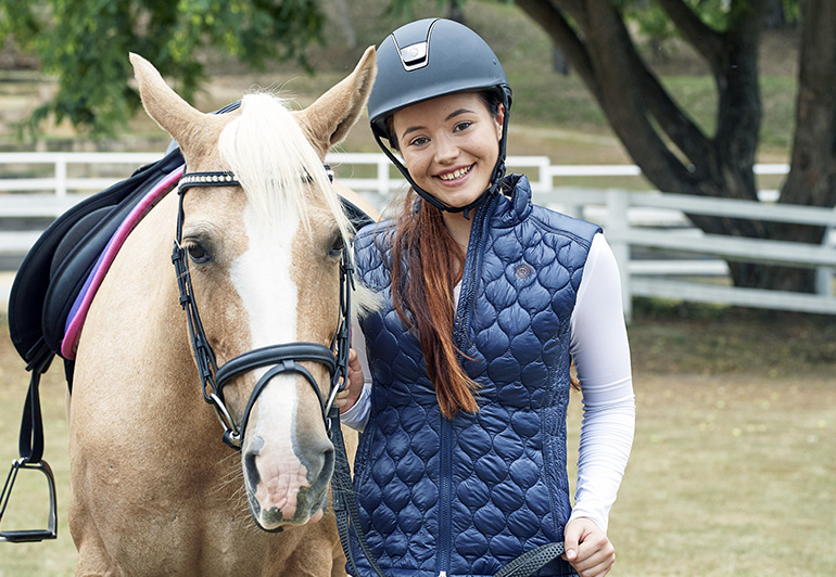 Headshot of Em Wayman standing next to a horse