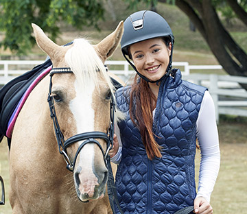 Headshot of Em Wayman standing next to a horse