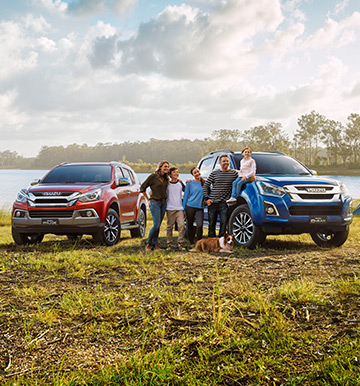 Family standing next to their Isuzu D-MAX and MU-X vehicles